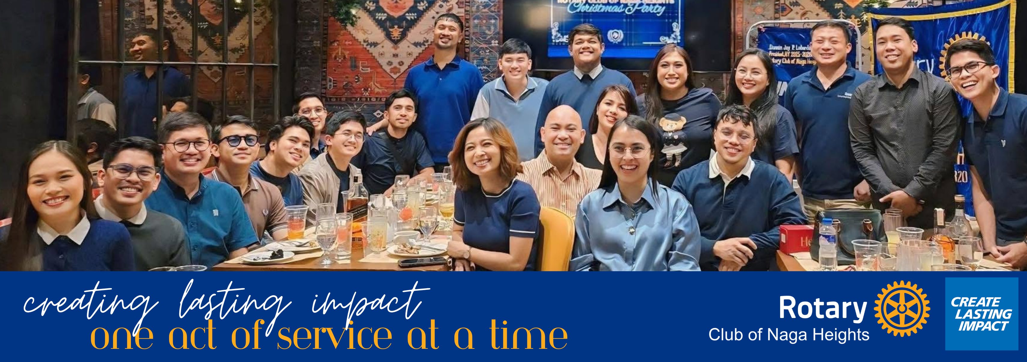 Rotary Club of Naga Heights members celebrating together at a club Christmas party, with the club's Create Lasting Impact theme banner.